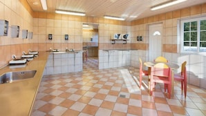 Une cuisine spacieuse avec un carrelage à motifs, un îlot central et un coin repas agrémenté de chaises roses.