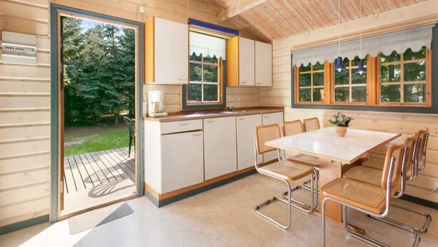 Une cuisine compacte avec un coin repas, des murs en bois et de grandes fenêtres.