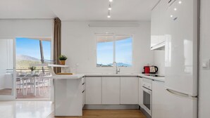 A modern kitchen with white cabinetry, a built-in oven, and a coffee maker on the counter.