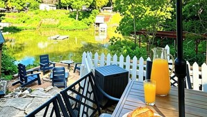 An outdoor seating area with a table, chairs, and a table umbrella. - Hot Tub, Fire pit, Cabana, Covered Patio & Pet-friendly Riverside Retreat (New Braunfels)
