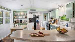 A kitchen with a central island, a dining area, and a view of the living room. - Hot Tub, Fire pit, Cabana, Covered Patio & Pet-friendly Riverside Retreat (New Braunfels)