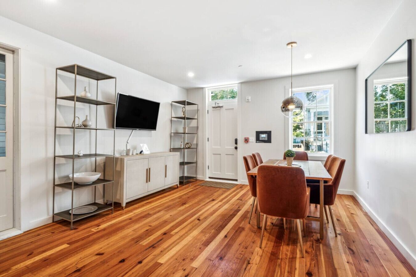 Un espace repas moderne avec un plancher en bois, des murs blancs et une table à manger entourée de chaises.