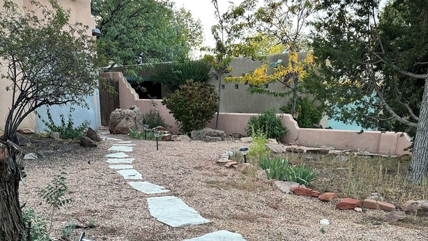 A stone pathway leading through a garden with various plants and trees. - Cozy studio in charming Santa Fe (Santa Fe)