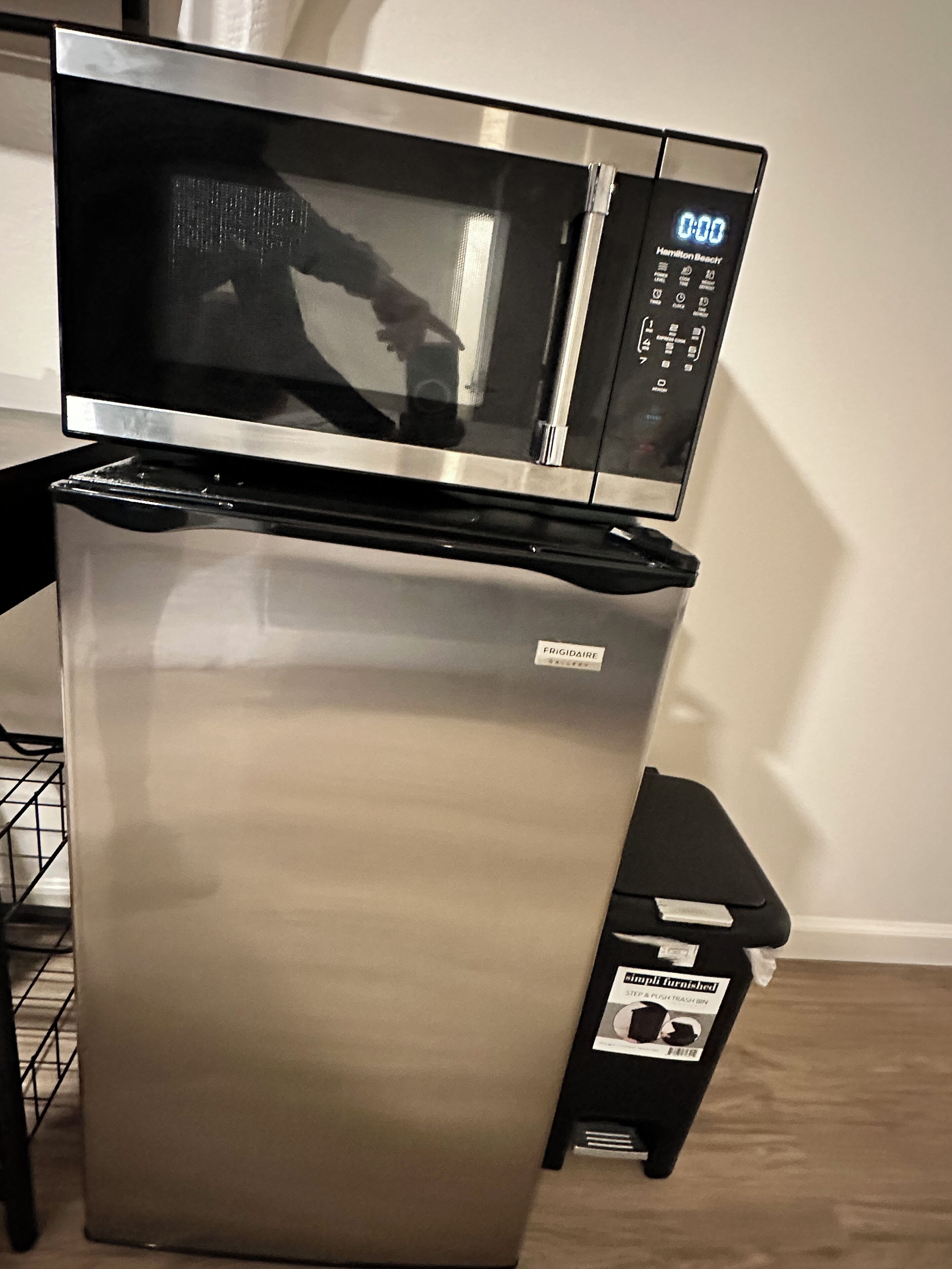 A stainless steel refrigerator with a digital display and a trash bin labeled "Simple Furnished."