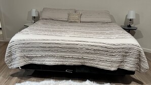 A bed with a textured blanket, two bedside lamps, a fluffy rug, and a wooden floor. - Cozy studio in charming Santa Fe (Santa Fe)