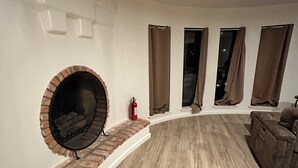 A modern living room with a brick fireplace, a wooden floor, and a brown sofa. - Cozy studio in charming Santa Fe (Santa Fe)