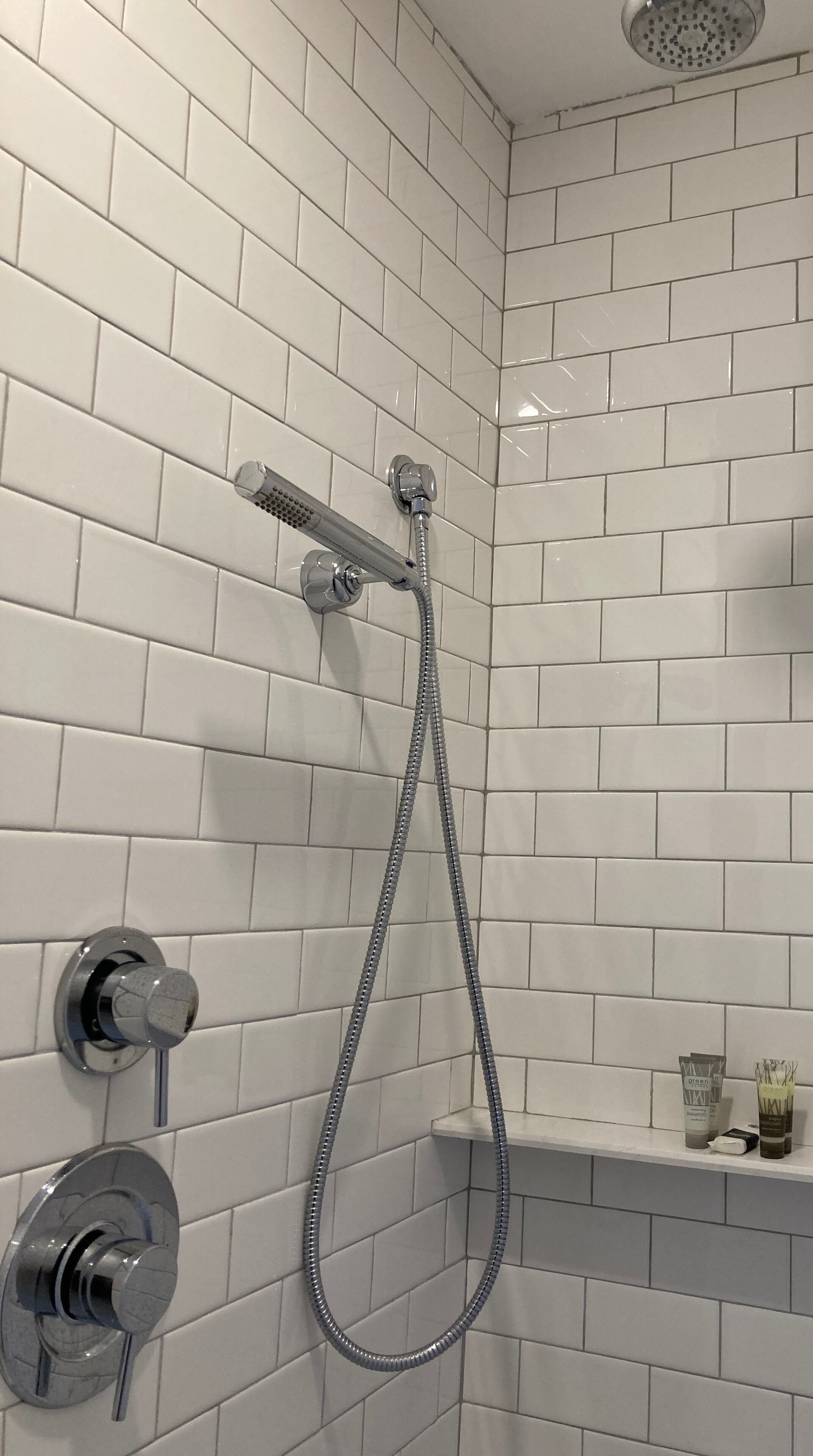 A shower with a handheld showerhead and a wall-mounted faucet.