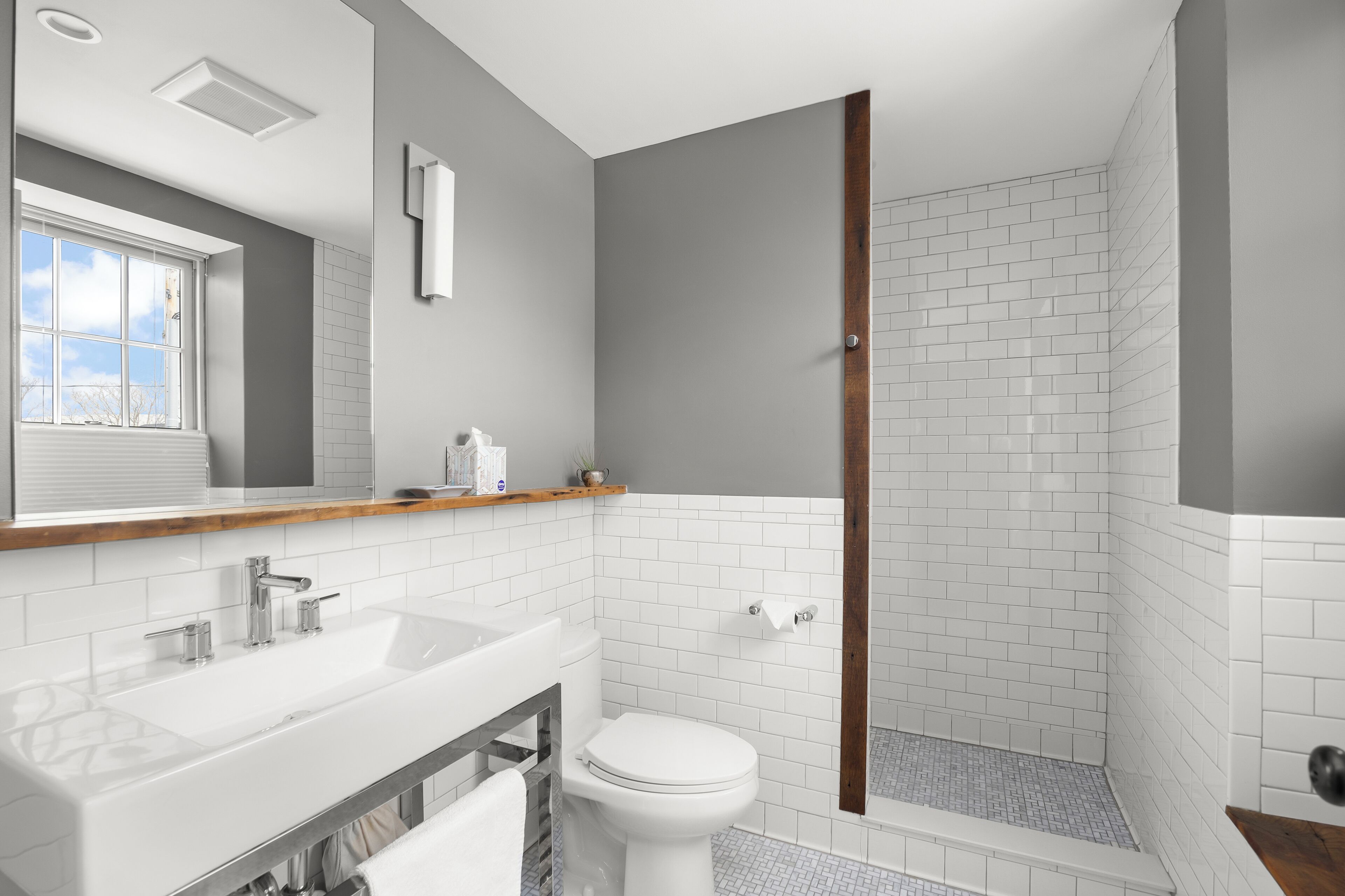 A modern bathroom with a white sink, a toilet, and a shower area.
