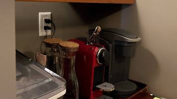 Una cocina con cafetera, tarros y un cesto de cápsulas de café.