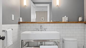 Een badkamer met een wit wastafel, twee kranen, een spiegel en een toilet.