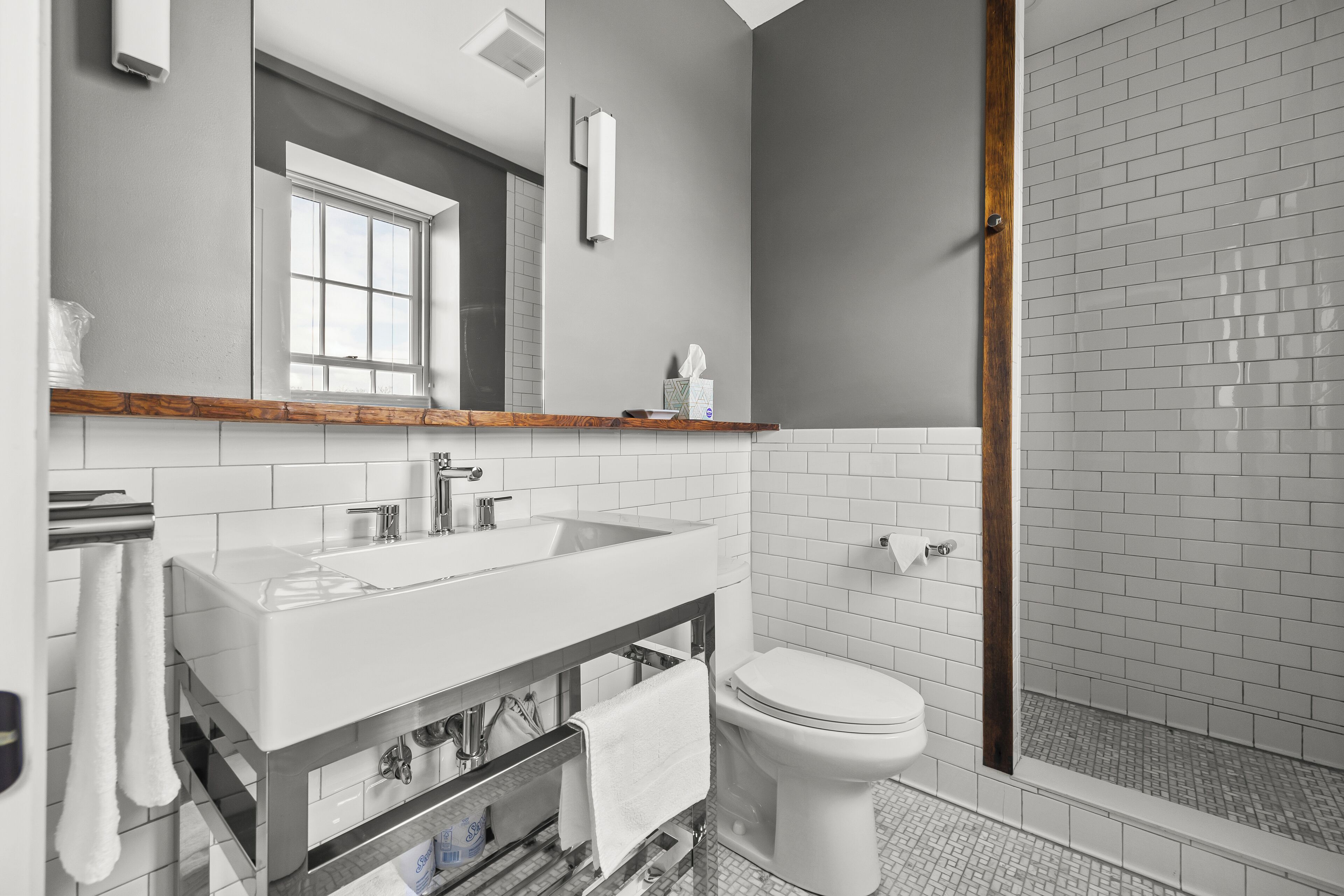 Un bagno moderno con uno specchio grande, un lavandino bianco e una zona doccia.