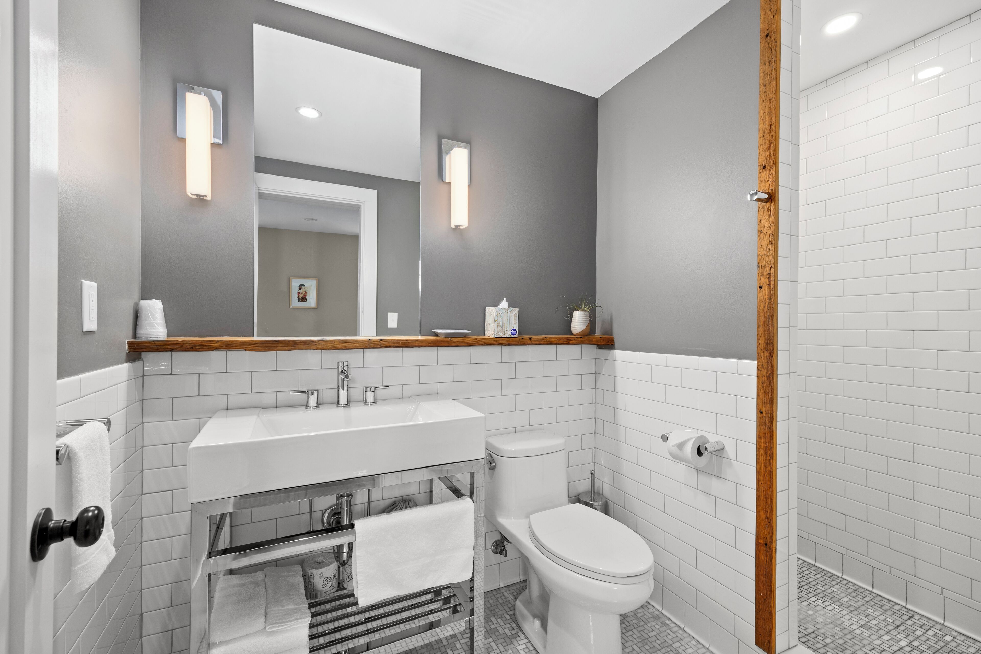 A modern bathroom with a white sink, toilet, and shower area.