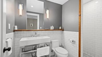 A modern bathroom with a white sink, toilet, and shower area.