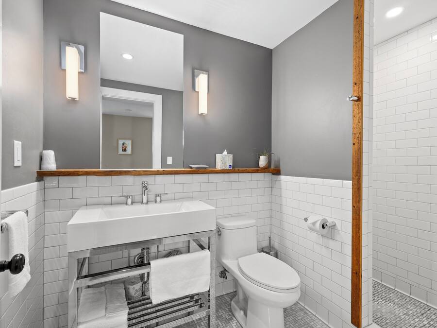 A modern bathroom with a white sink, toilet, and shower area.