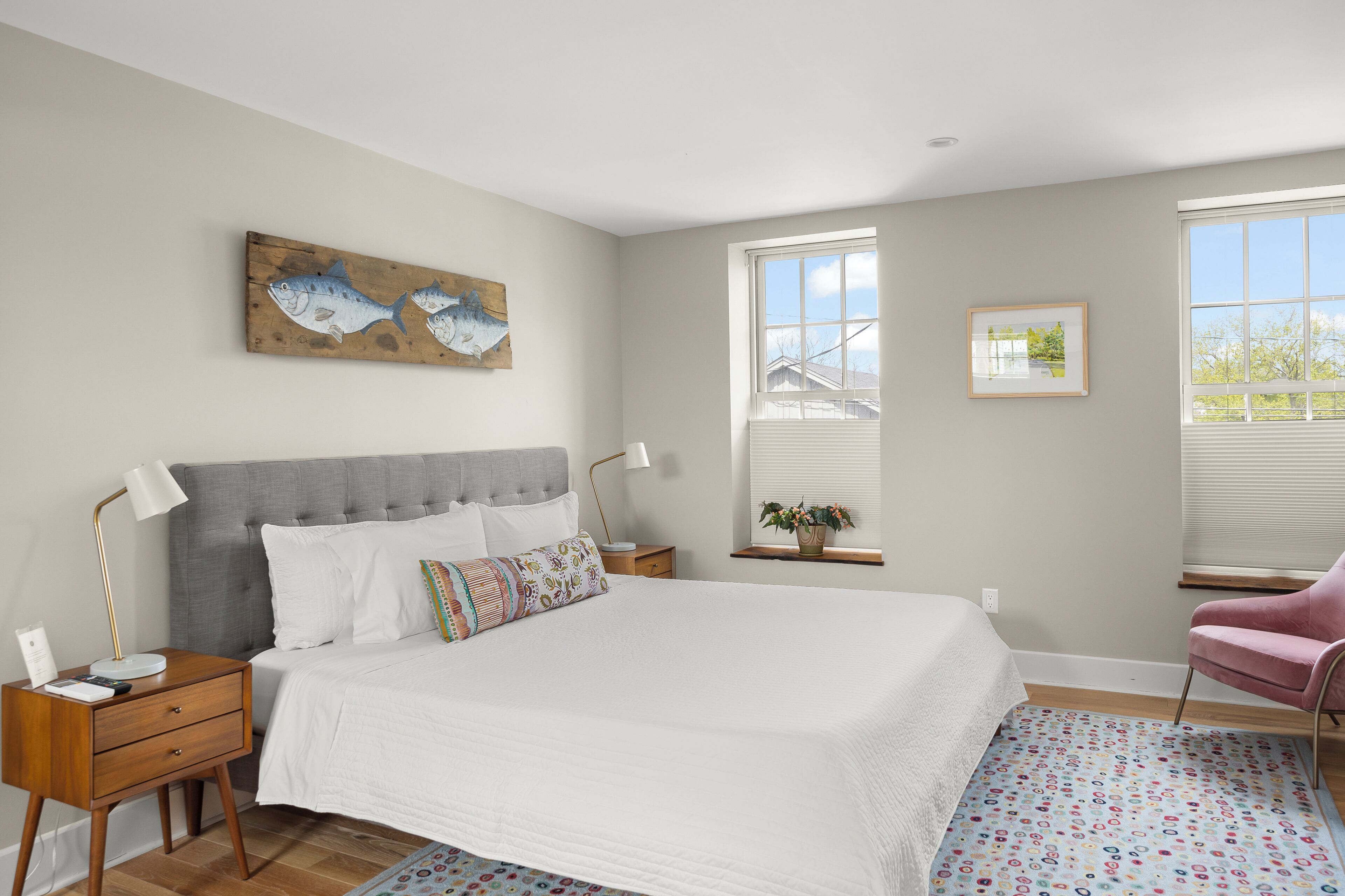 A bedroom with a large bed, a nightstand, a chair, and a window with blinds.