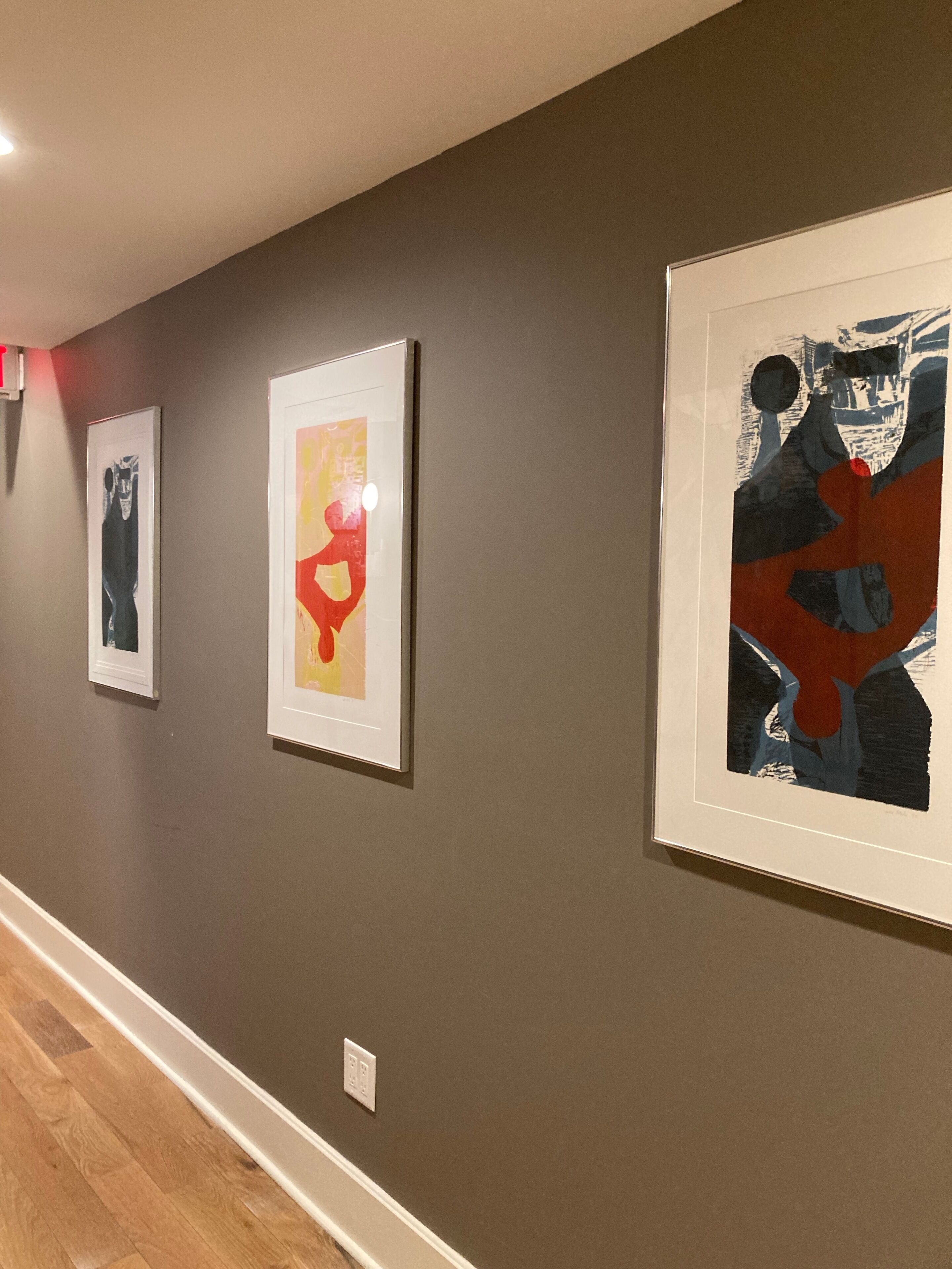 A hallway with three framed artworks on the wall.