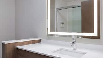 A modern bathroom with a white sink, a mirror with integrated lighting, and a wooden vanity.