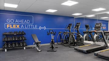 Une salle de sport équipée de tapis de course, de vélos elliptiques et d’un banc de musculation.