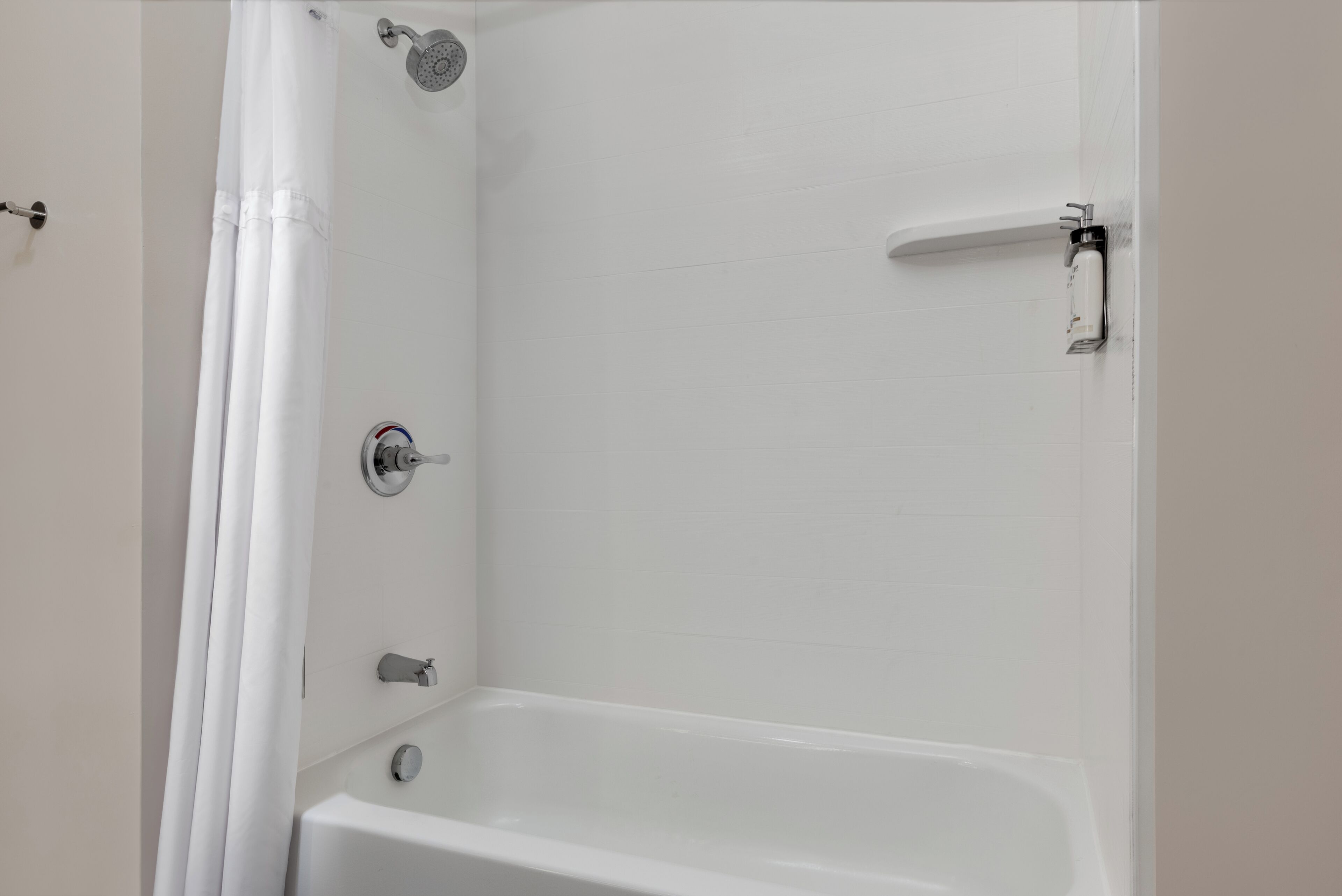 A bathroom with a bathtub, a showerhead, and a toilet.