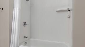 A bathroom with a bathtub, a showerhead, and a toilet.
