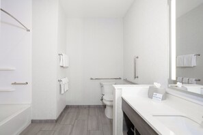 A modern bathroom with a toilet, a handrail, a towel rack, and a sink with a mirror. - Holiday Inn Express & Suites Stevensville Benton Harbor by IHG (Stevensville)