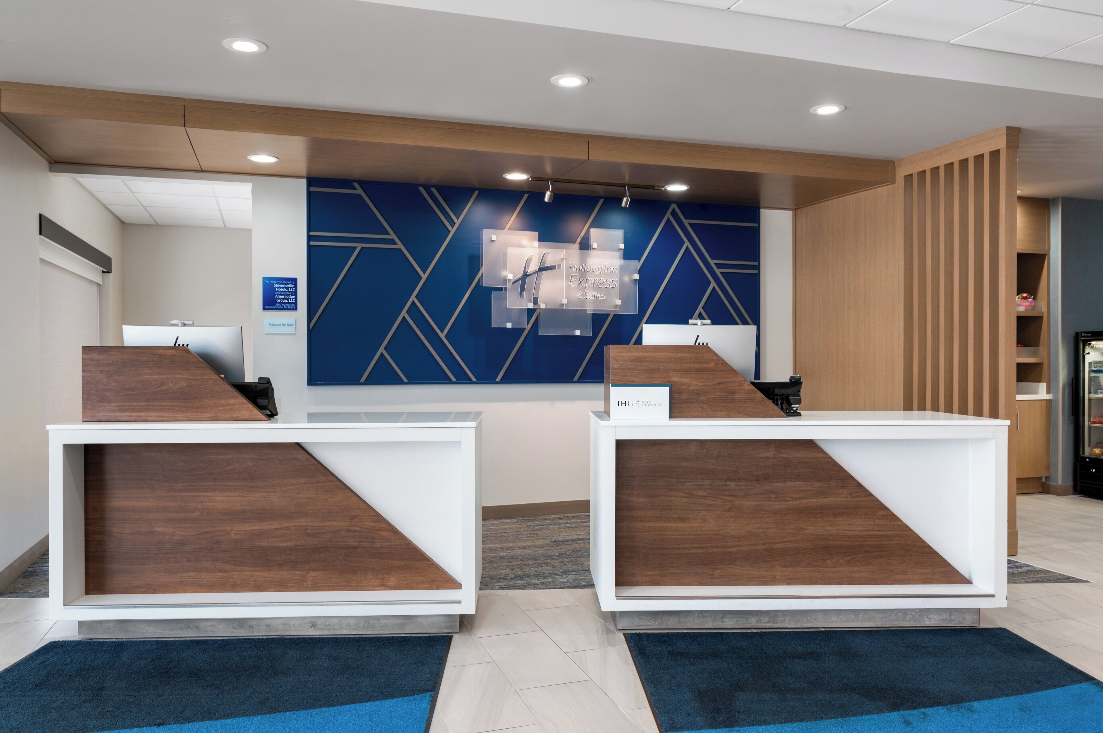 Un área de recepción con dos mostradores de madera, un diseño de pared geométrico azul y un cartel que indica 'Valley Inn Express'.