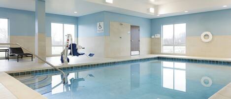 An indoor swimming pool with a lifeguard chair, a pool lift, and a window.