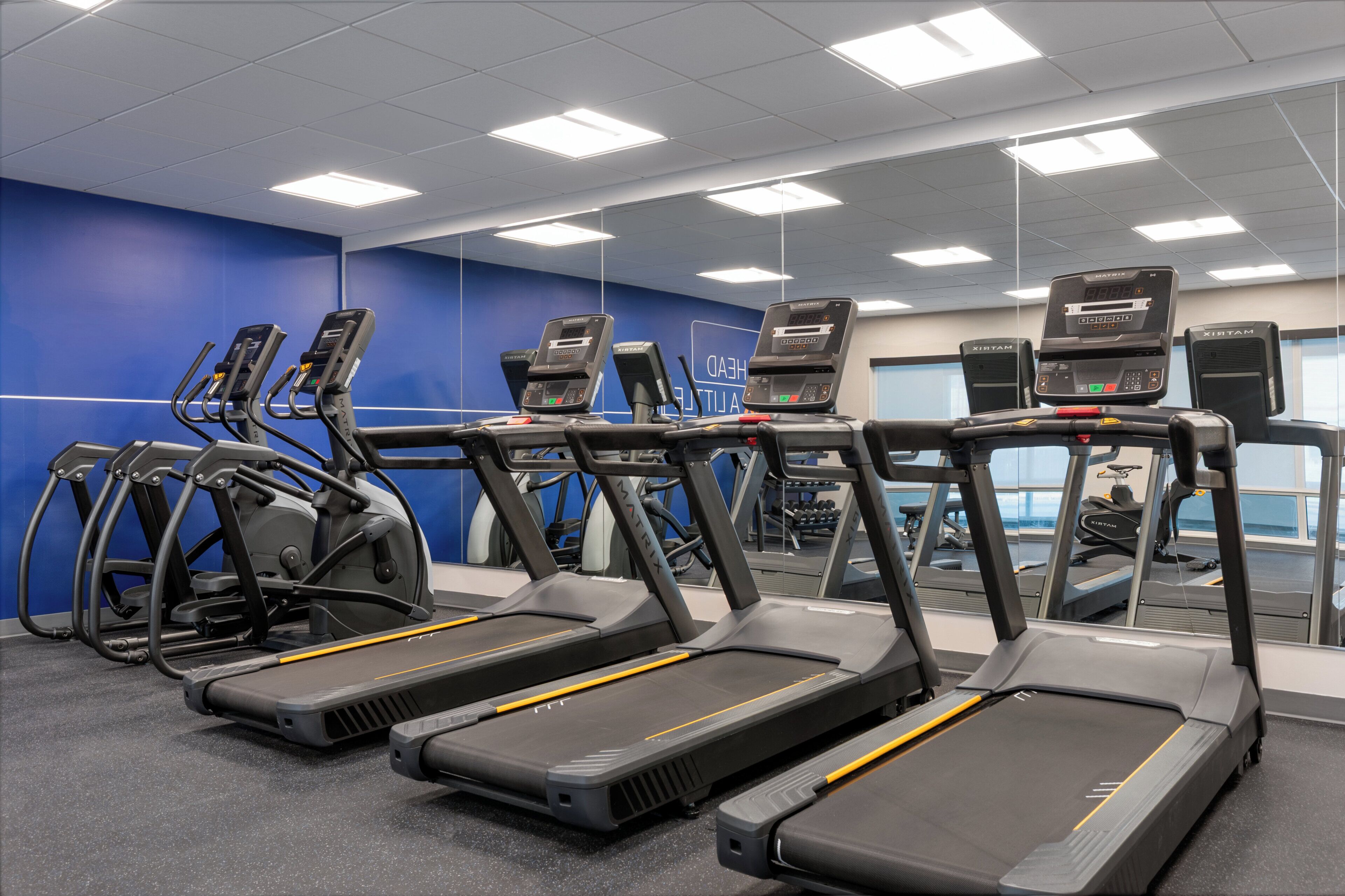 Un gimnasio con cintas de correr y máquinas elípticas.