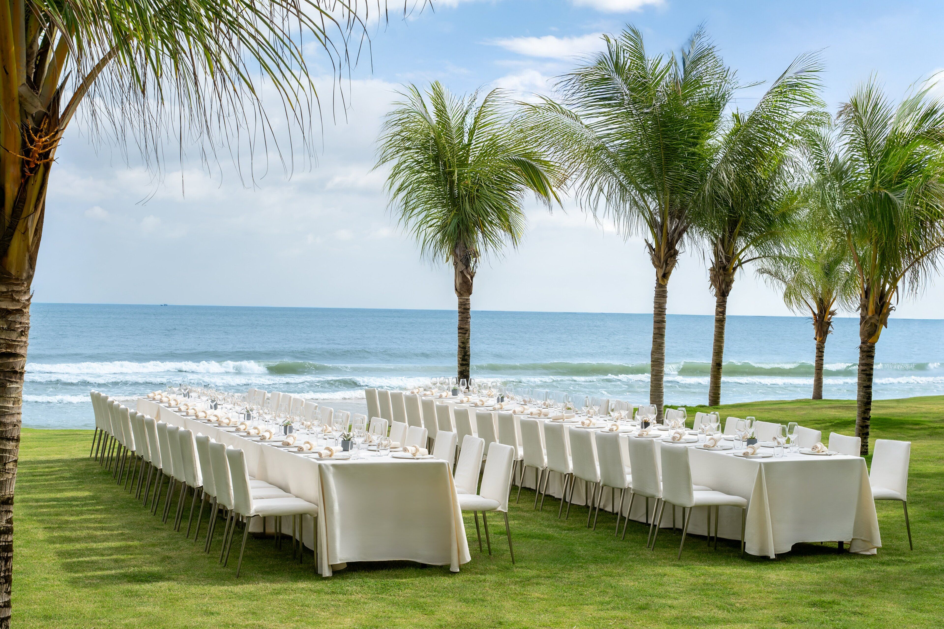 An outdoor dining area with tables set for a meal, overlooking the ocean.