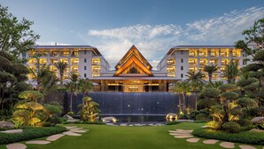 A modern hotel with a symmetrical facade, a central atrium, and a landscaped garden with a water feature. - Kimpton Aqeos Hainan by IHG (Lingshui)