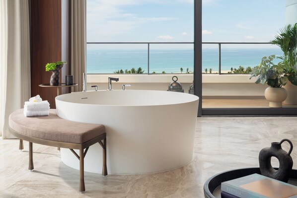 Une salle de bain moderne avec une baignoire sur pieds, un banc et une vue sur l’océan.