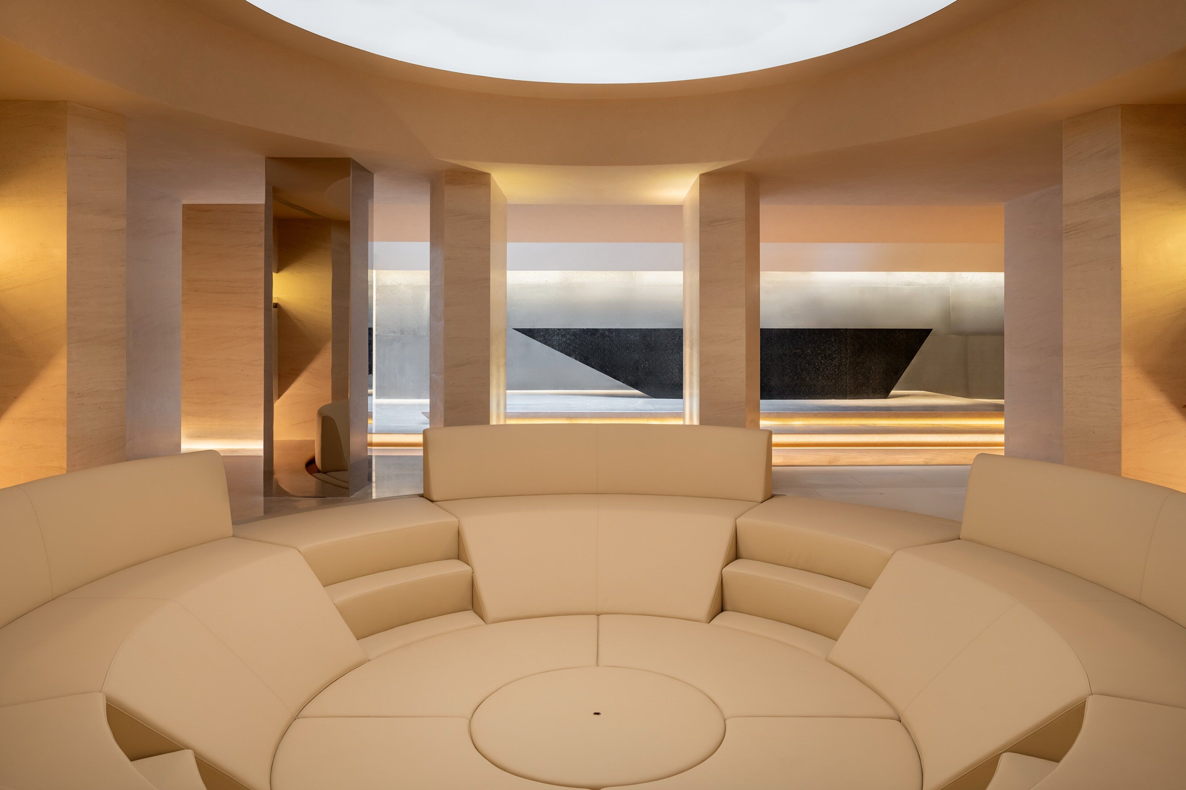 A modern, circular seating area with a central table, surrounded by high, cylindrical columns and large windows.