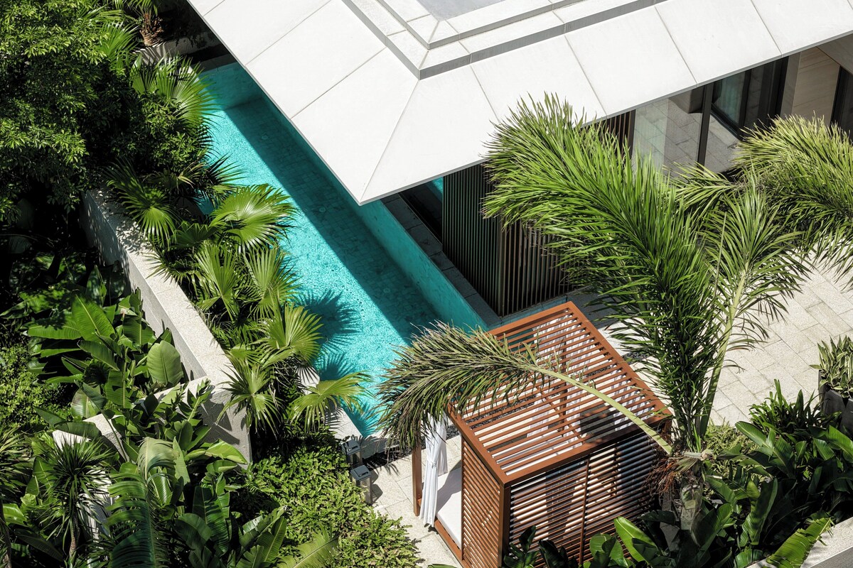 A modern building with a pool surrounded by lush greenery.