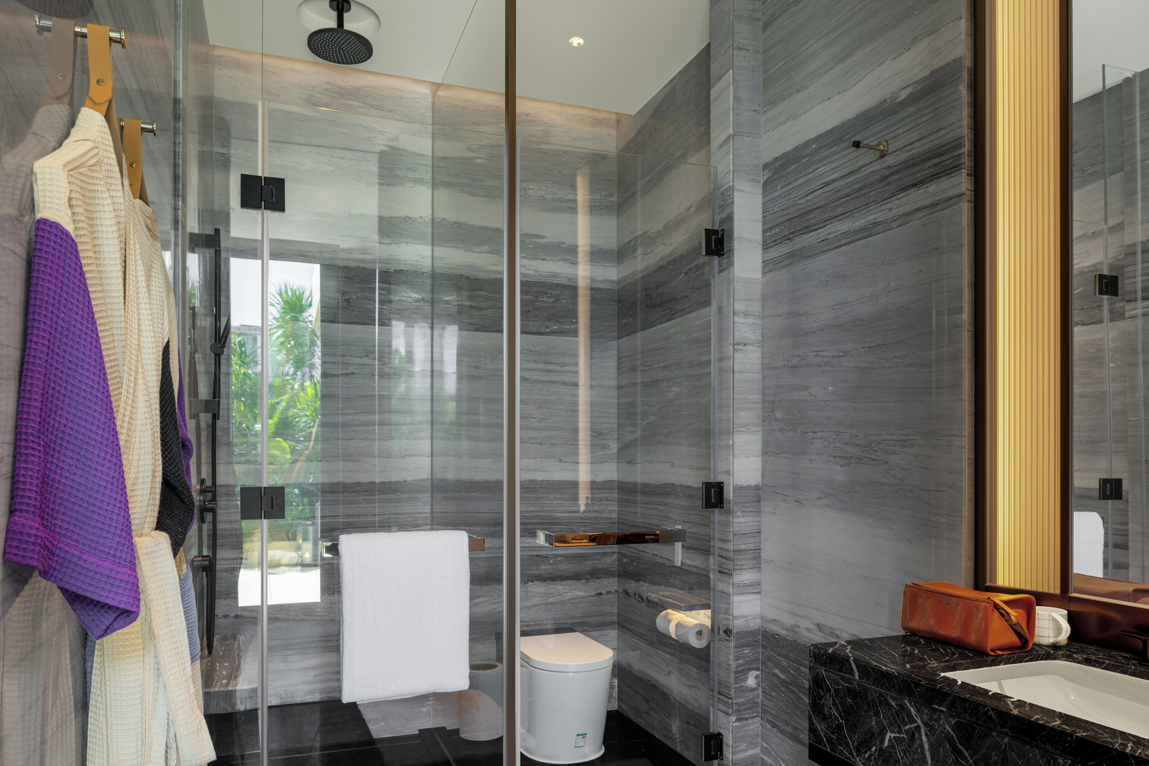 A modern bathroom with a glass-enclosed shower, a marble sink, and a large mirror.