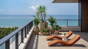 A balcony with a view of the sea, potted plants, and lounge chairs. - Kimpton Aqeos Hainan by IHG (Lingshui)