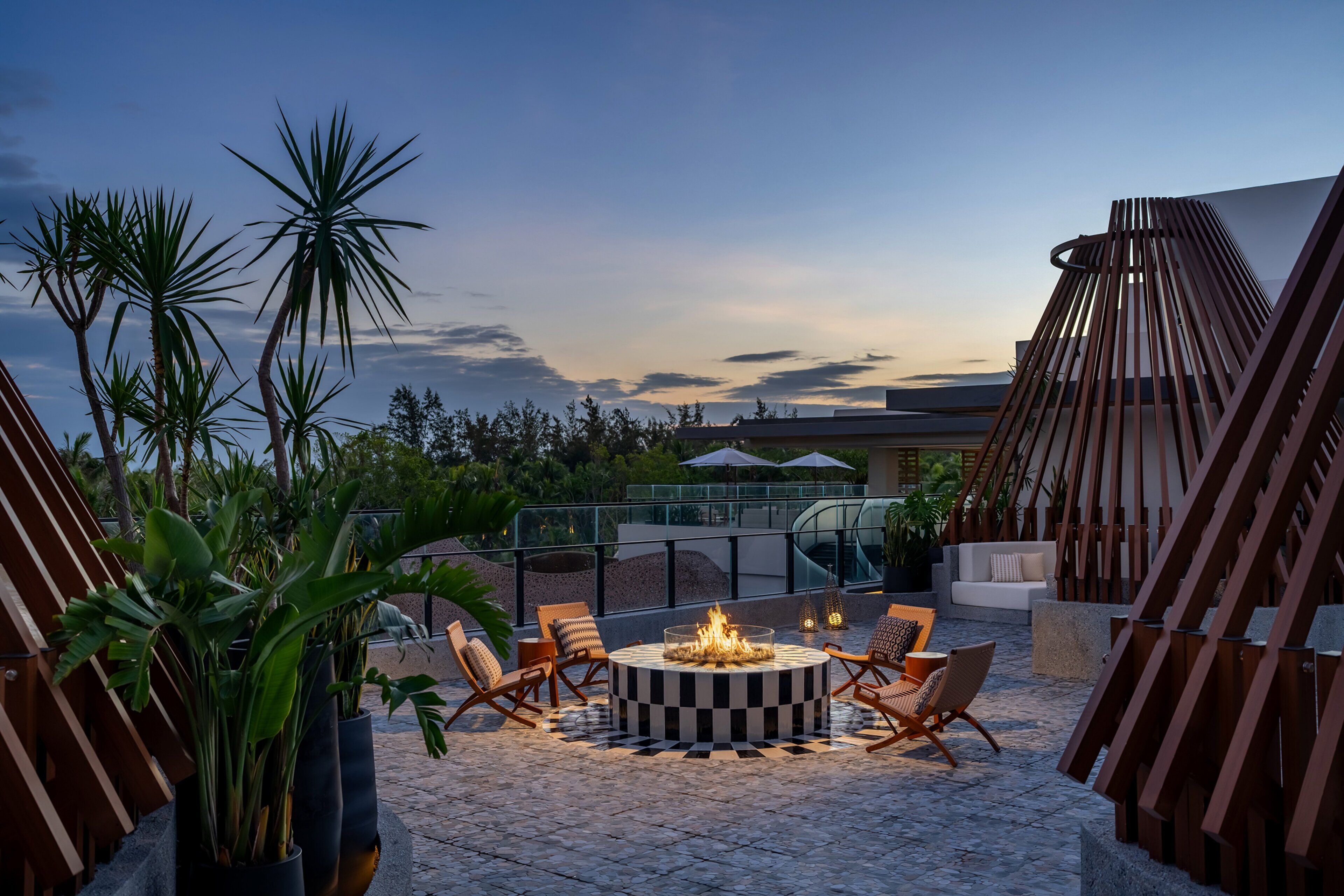 Terraza en la azotea con un hogar circular, sillones de descanso y plantas en macetas.