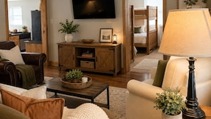 Una sala de estar con televisión, sofá, sillón, mesa de centro y lámpara.