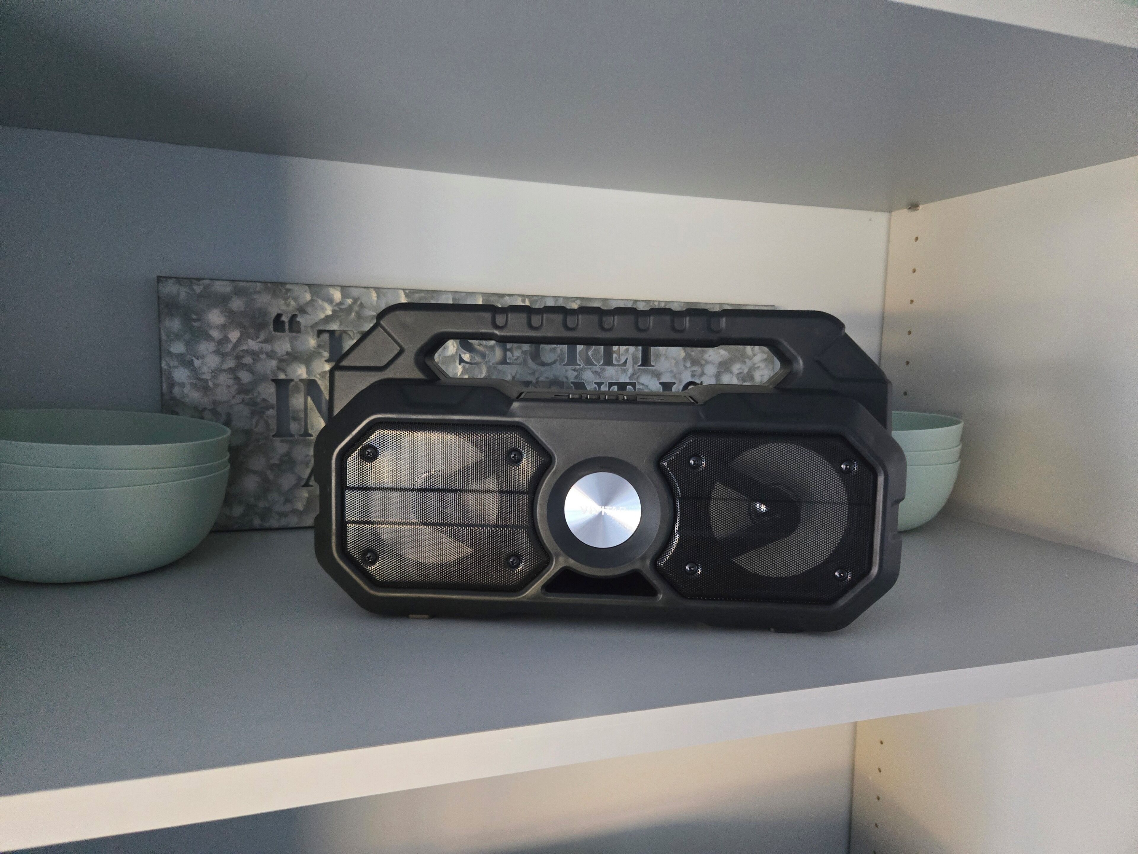 Une radio posée sur une étagère, avec un mur à texture et deux bols.