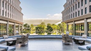Eine moderne Lounge-Bereich im Freien mit Sitzgelegenheiten und Tischen, umgeben von einem Pool und viel Grün.