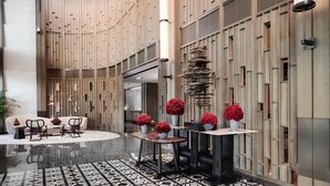 Eine moderne Lobby mit einer zentralen Sitzecke, einem gemusterten Boden und einer Wand mit vertikalen Paneelen.