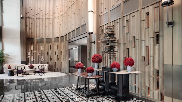 A modern lobby with a central seating area, a patterned floor, and a decorative wall with vertical panels. - HUALUXE Chongqing Science Hall by IHG (Chongqing)