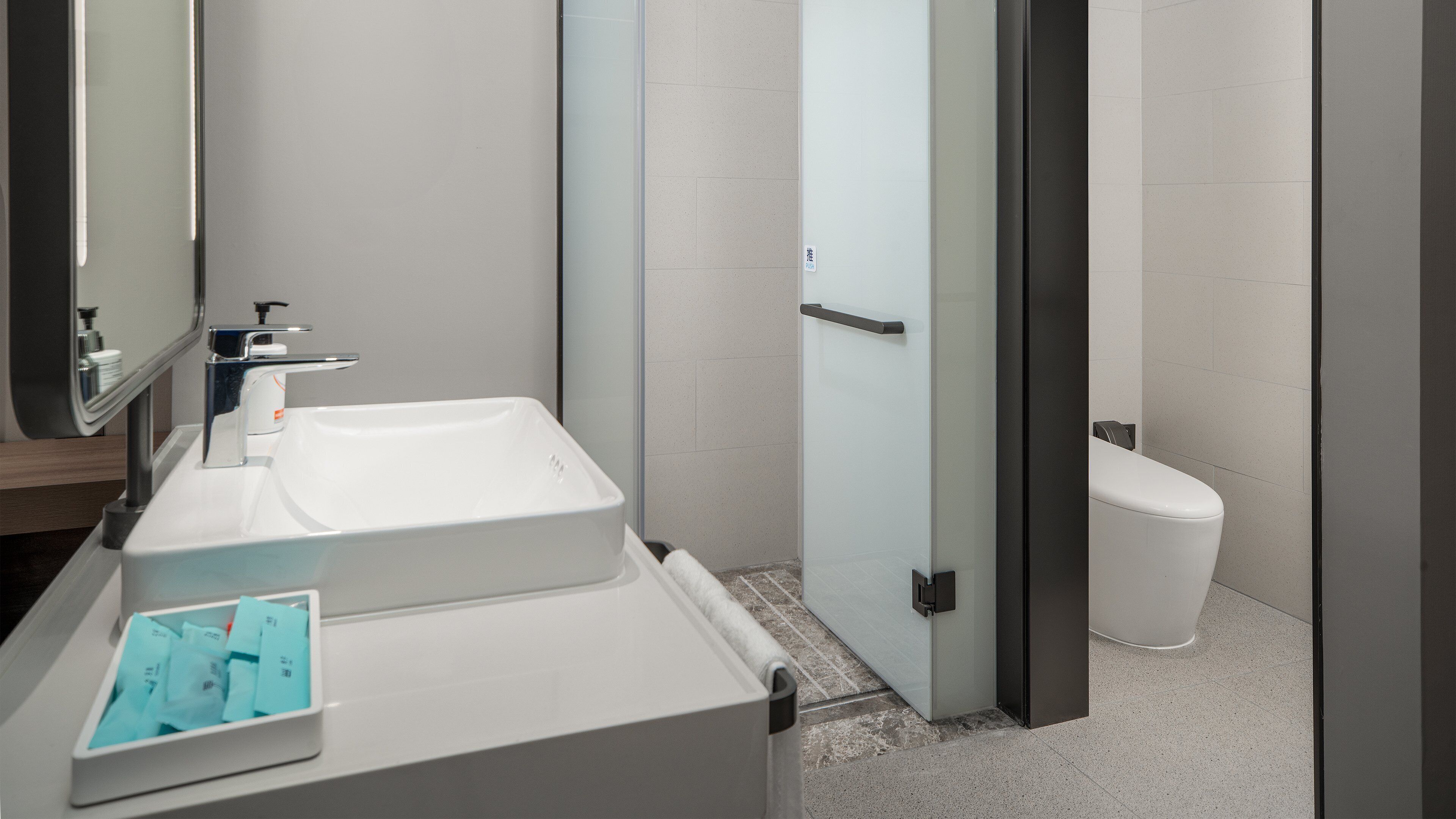 Ein modernes Badezimmer mit Waschbecken, Spiegel und Toilette in Weiß.