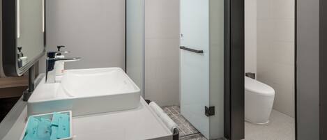 Un baño moderno con lavamanos, espejo y retrete blancos.