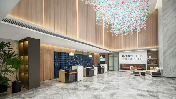 Un hall d’entrée moderne avec un comptoir d’accueil, un espace salon et une cheminée.