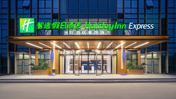 A hotel entrance with a modern design, featuring a glass facade and a covered entrance area.
