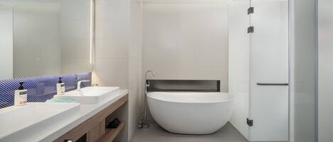 Un baño moderno con una bañera independiente, un espejo grande y un tocador con dos lavamanos.