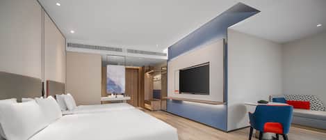 Una camera d'albergo moderna con un letto grande, una scrivania con sedia, una TV e un'area salotto con divano.