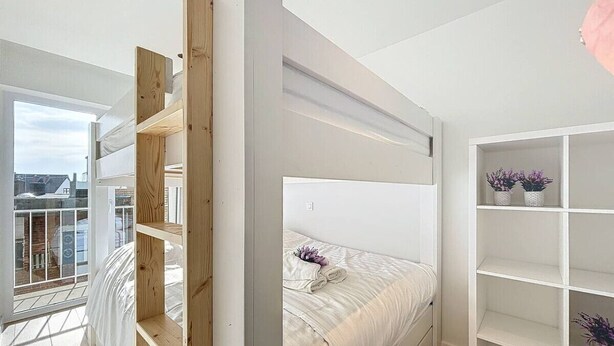 Een moderne slaapkamer met een stapelbed, een balkon met uitzicht en een wit wandrek.