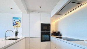 Een moderne keuken met witte kastjes, een inbouwoven en een spoelbak.
