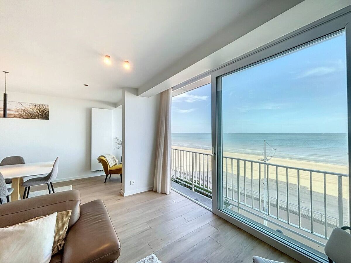 Un salon moderne avec un grand balcon donnant sur une plage.